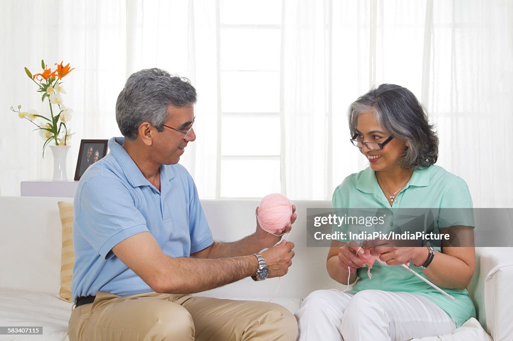 Husband helping while his wife is knitting