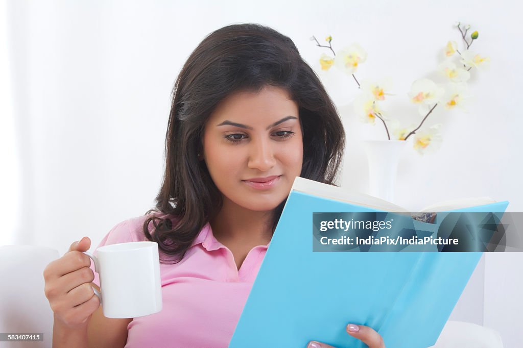 Woman with a mug of tea reading a book