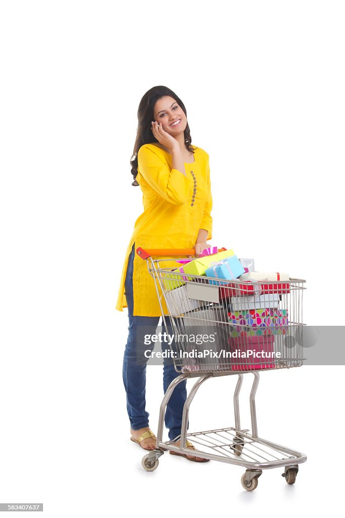 Woman with shopping cart talking on a mobile phone