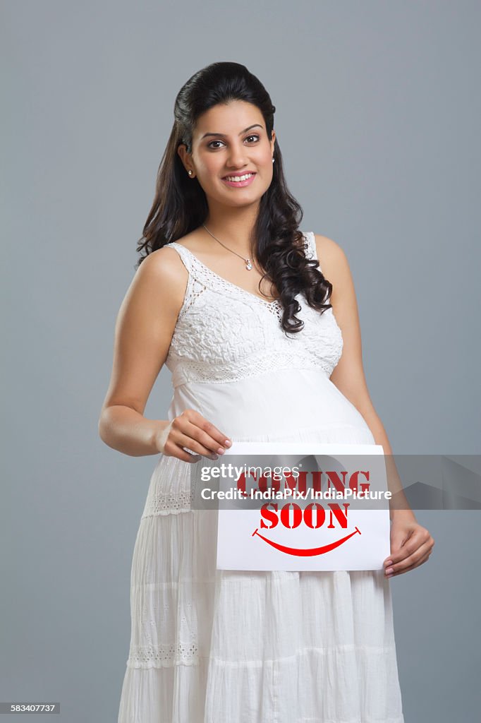 Portrait of a pregnant woman holding a message