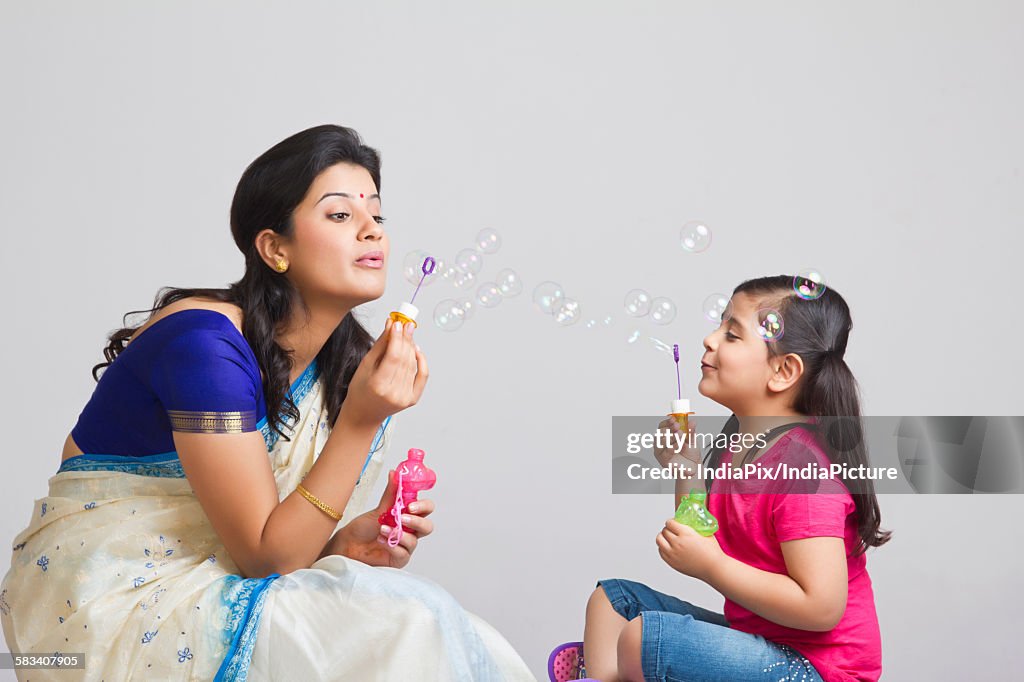 Mother and daughter blowing bubbles