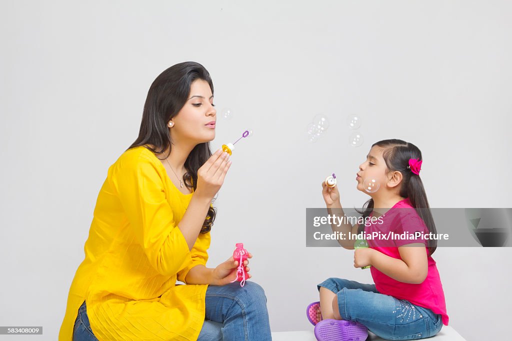 Mother and daughter blowing bubbles