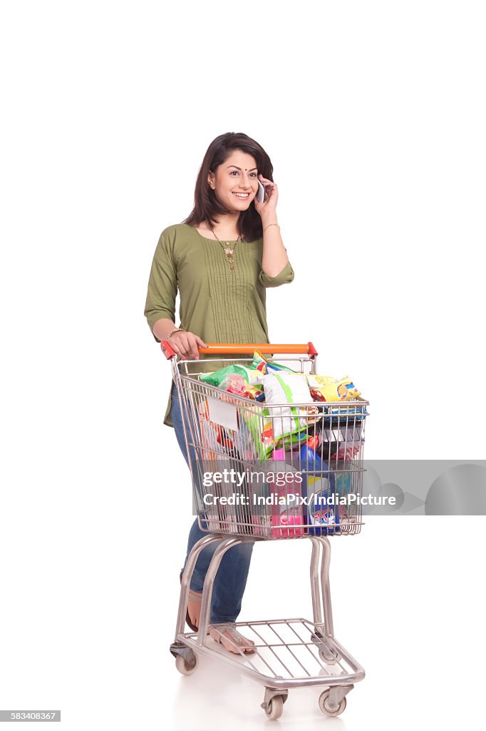 Married woman with shopping cart talking on mobile phone