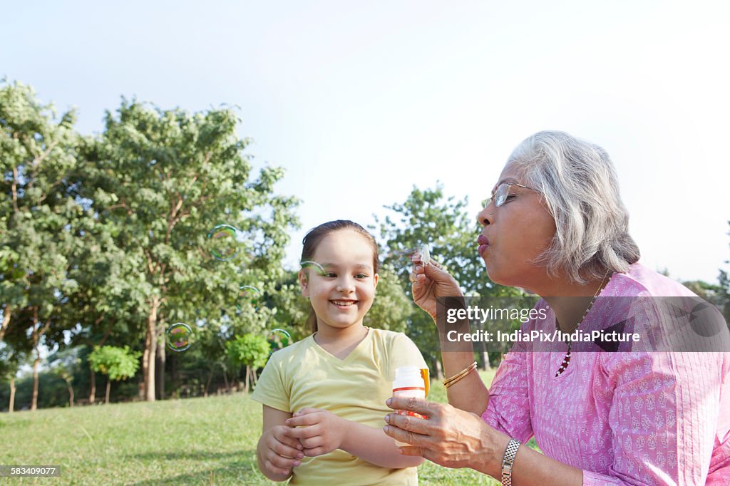 Grandmother blowing bubbles for granddaughter