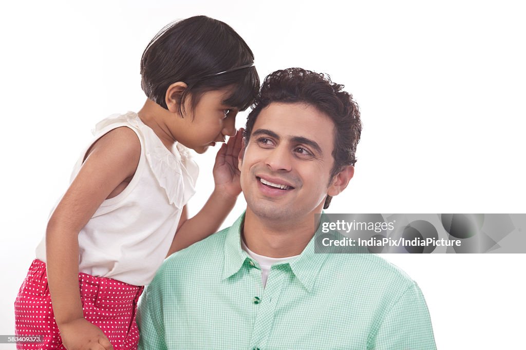 Girl whispering in fathers ear