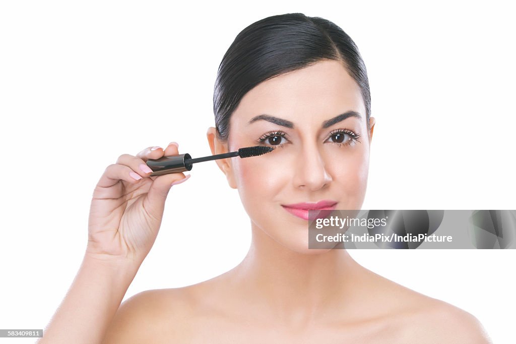 Portrait of a beautiful woman applying mascara