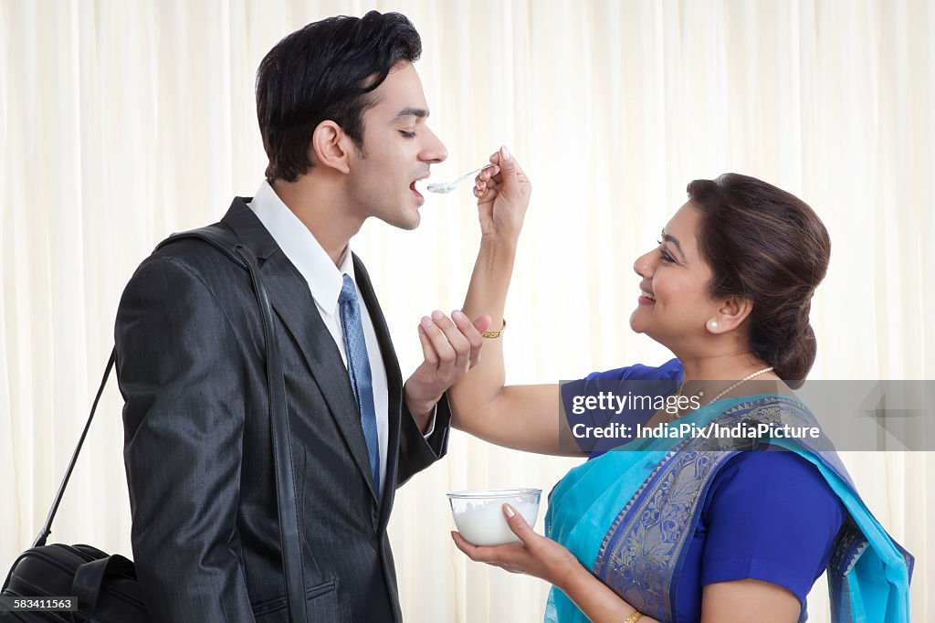 Mother feeding her son dahi