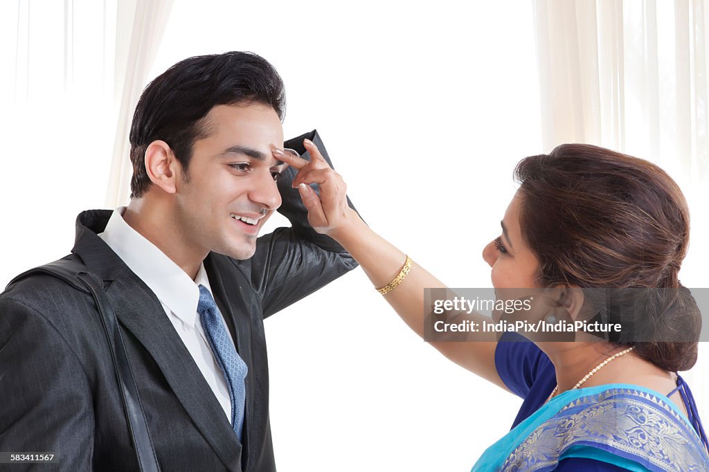 Mother putting a tikka on her sons forehead