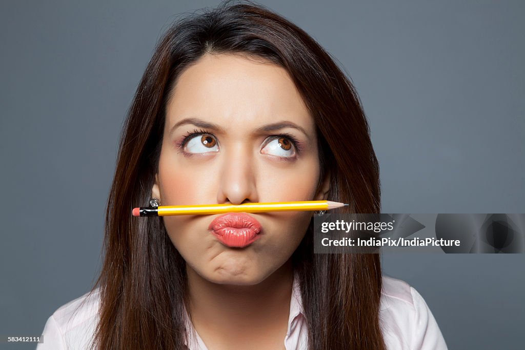 Female executive balancing pencil on lip