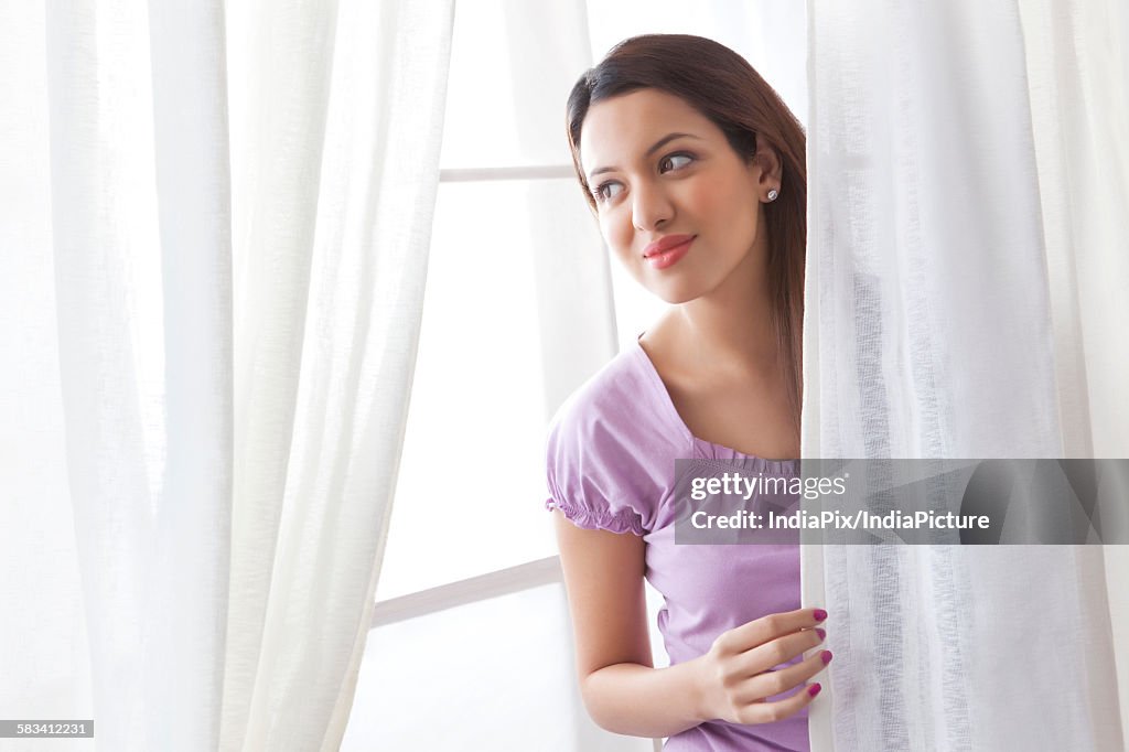 Young woman behind curtains