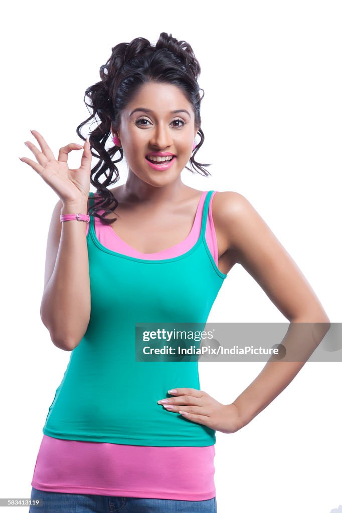 Portrait of young woman making ok hand gesture