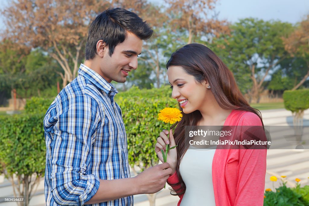 Young man giving a flower to a young woman