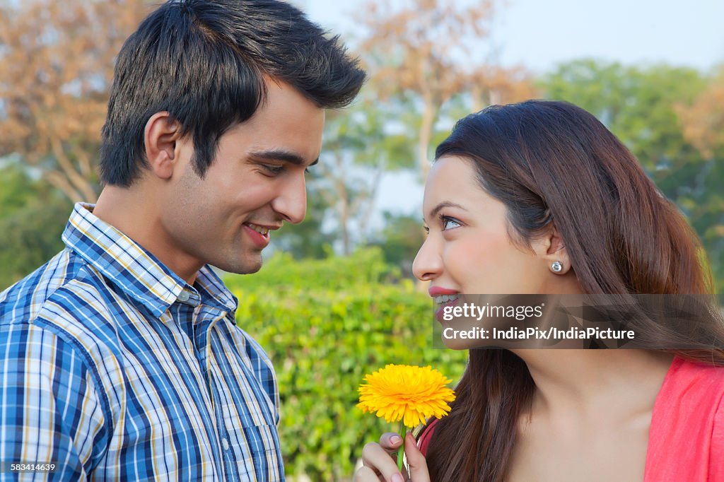 Young man giving a flower to a young woman