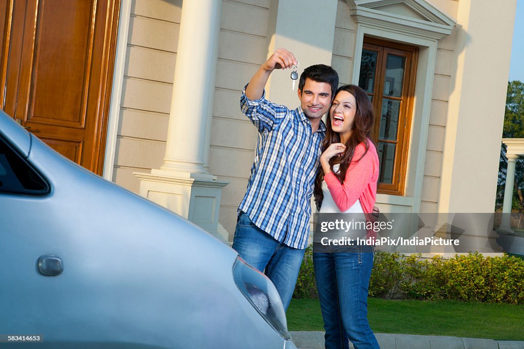 Young man shows car keys to young woman