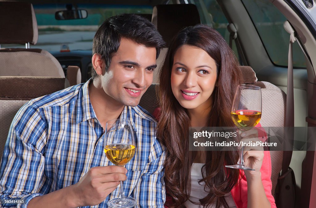 Young man and young woman sitting in the trunk of a car