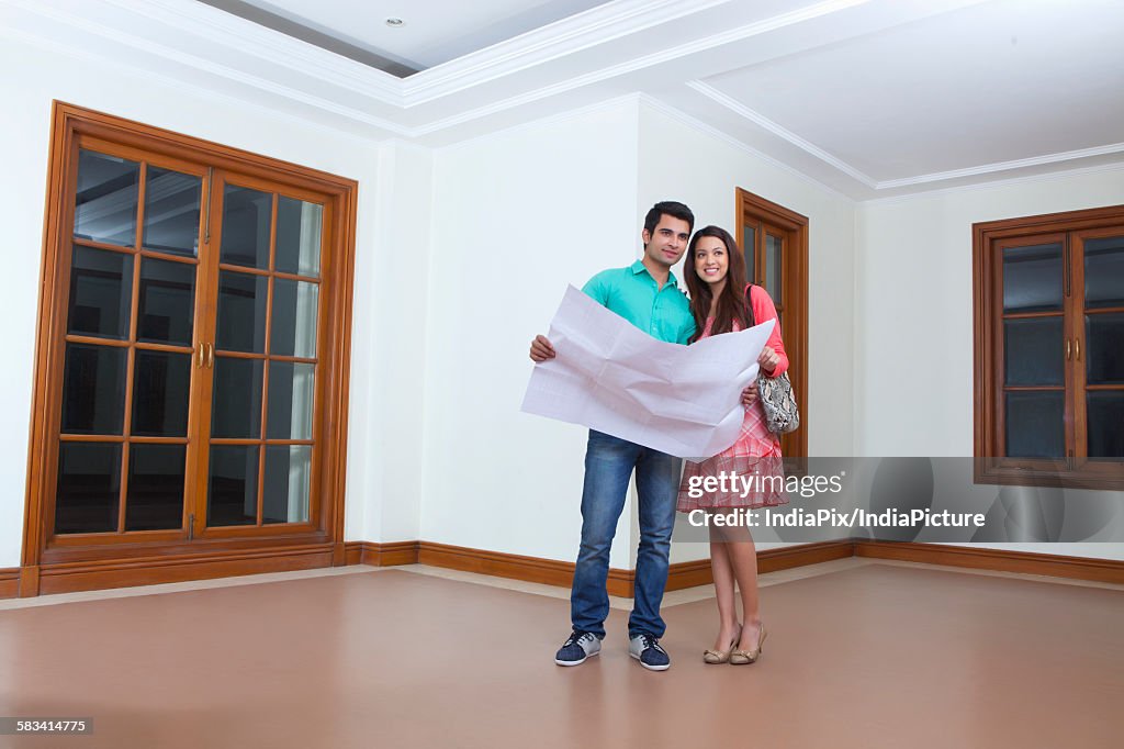 Young man and young woman looking at lay out of houseYoung man and young woman looking at lay out of house