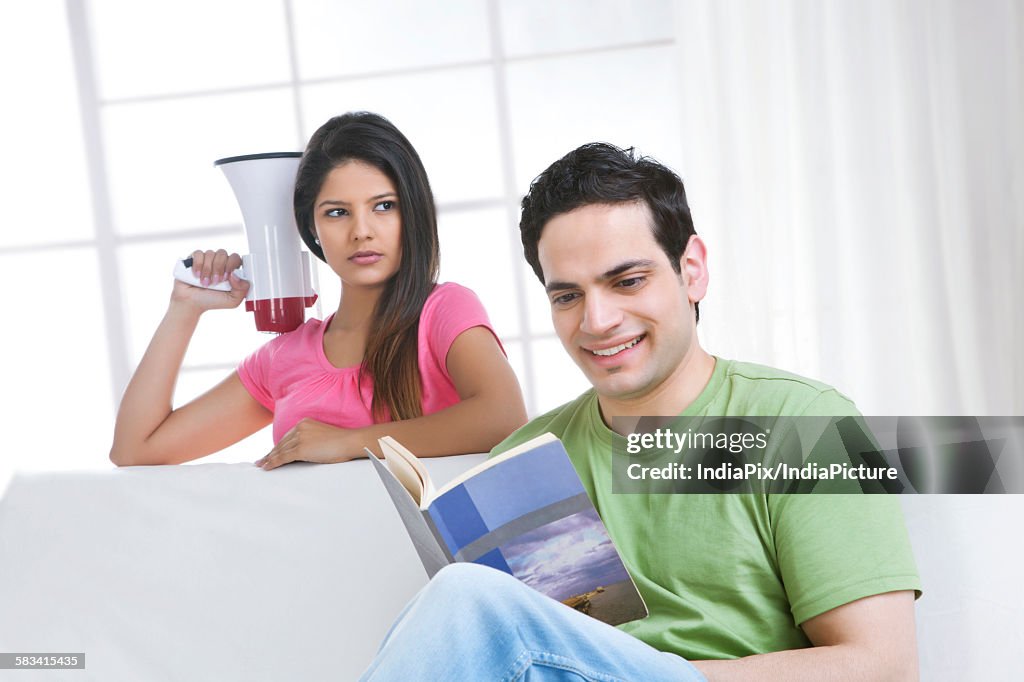 Young man reading while young woman looks over in anger