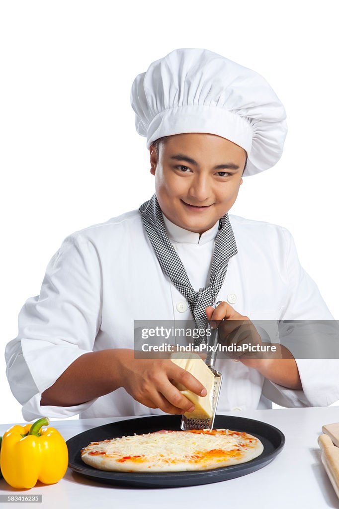 Portrait of chef grating cheese on pizza