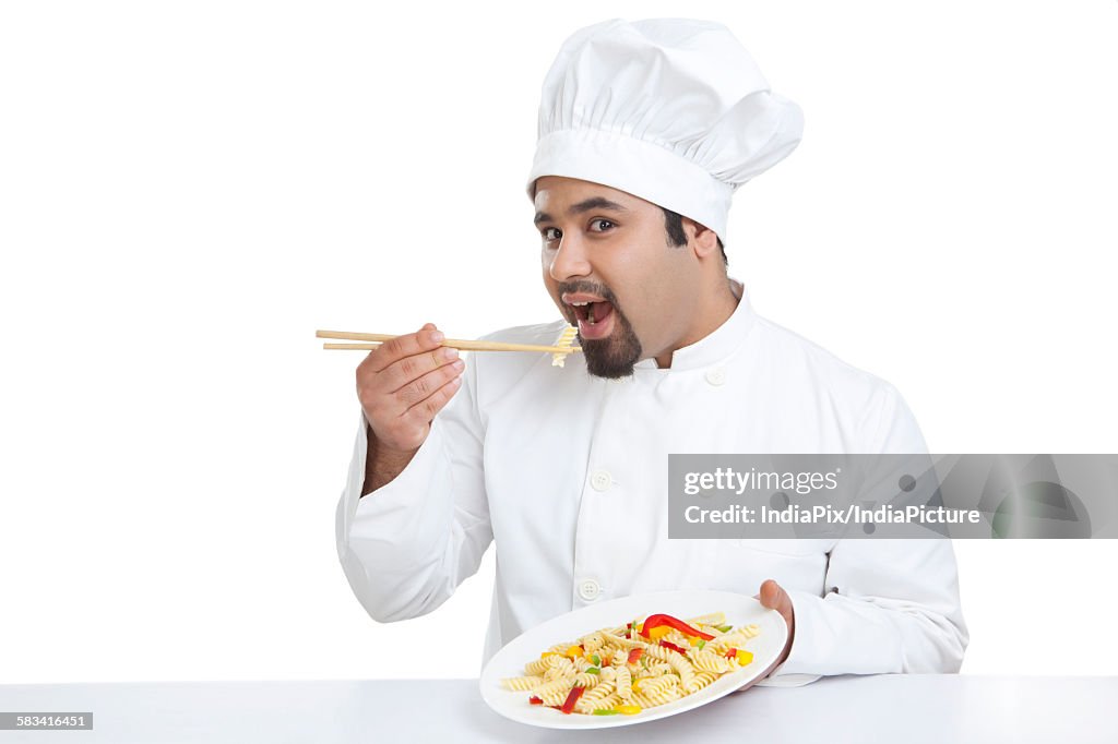 Portrait of chef eating pasta with chopsticks