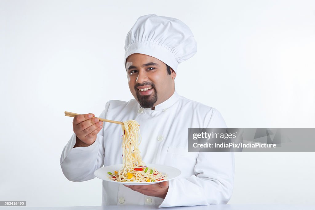 Portrait of chef lifting pasta with chopsticks