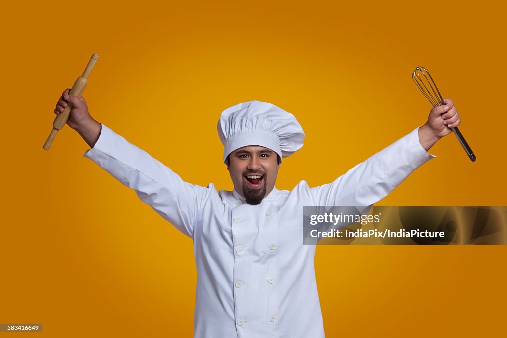 Portrait of chef holding wire whisk and rolling pin