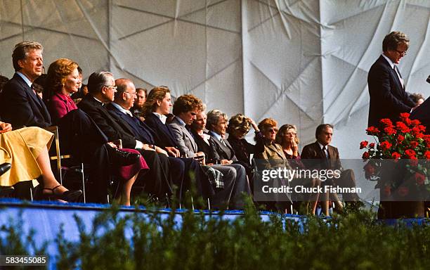 President Jimmy Carter, left, listens as Senator Edward Kennedy addresses the crowd from the podium at the dedication ceremony for the John F....