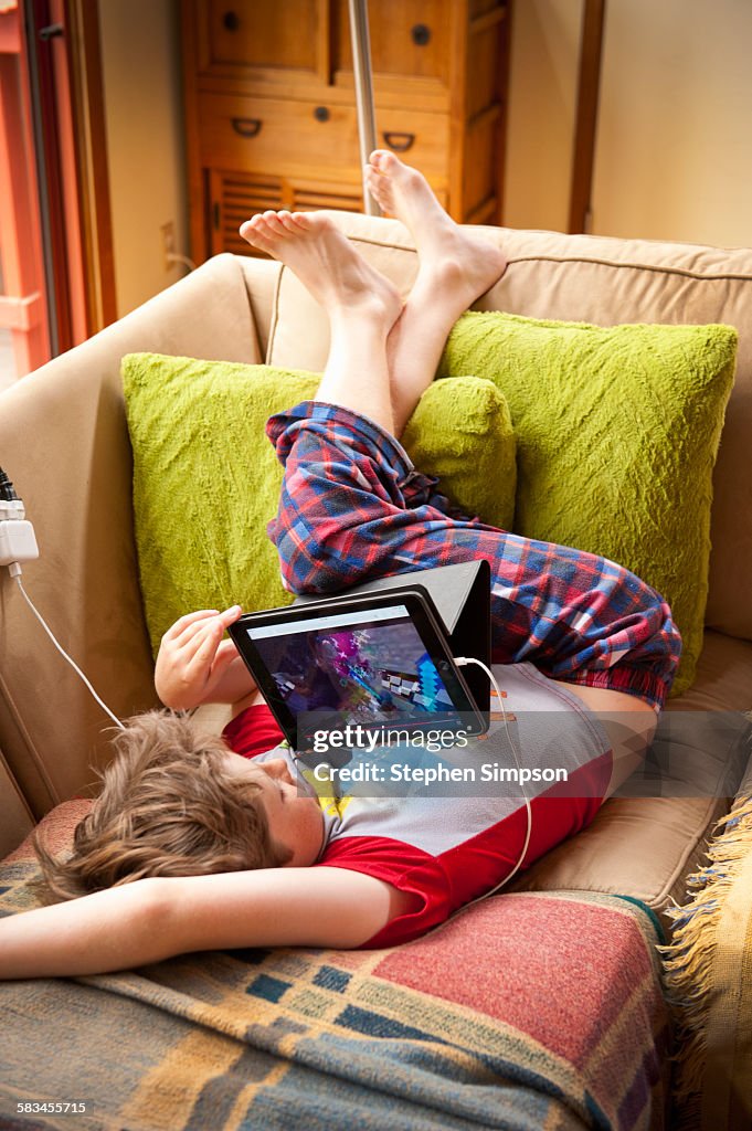 Boy in pajamas on couch with tablet
