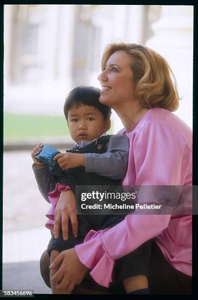 The wife of the French Minister of Culture, Dr. Marie-Yvonne Douste-Blazy, holds their adopted son lovingly.