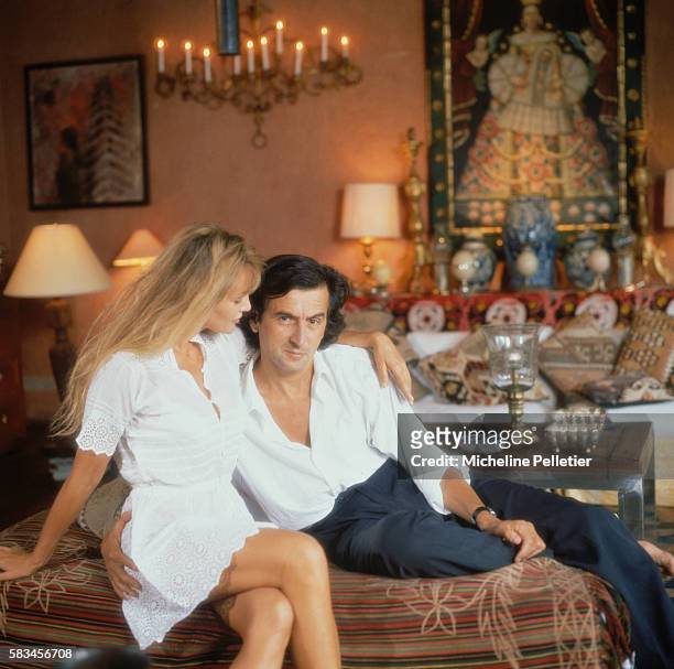 French actress Arielle Dombasle and French philosopher, writer and film director Bernard-Henri Levy sit on a sofa, in the living room of their...