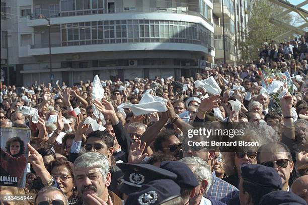 Thousands of white handkerchiefs flutter among the crowd in mourning.