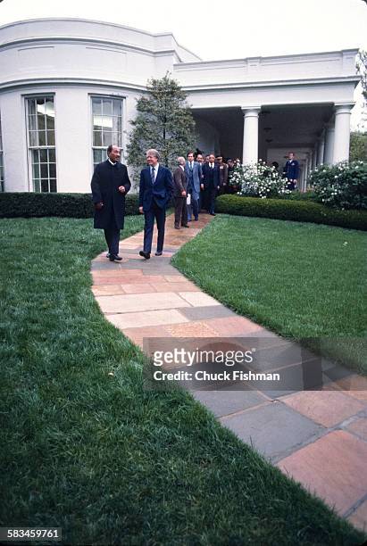 President Jimmy Carter, right, speaks and walks with Egyptian President Anwar Sadat as they leave the White House after exiting the Oval Office,...