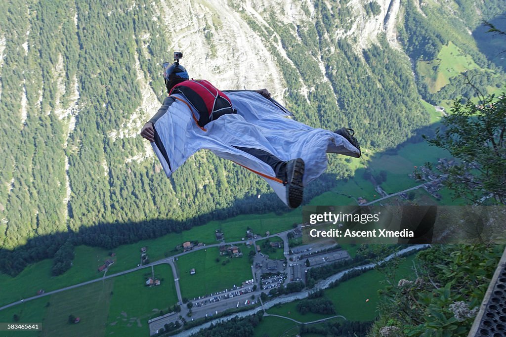 Wingsuit flier in airborne descent towards valley