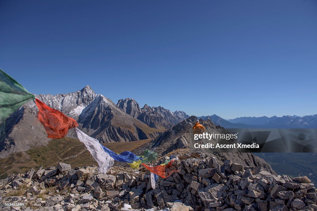 View past prayer flags to man on mountain summit