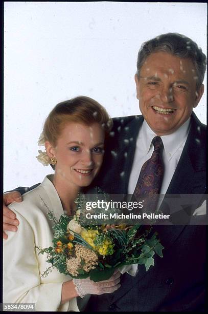 French entertainer Jacques Martin poses for a photo shoot with his wife Celine, who's holding a flower bouquet.