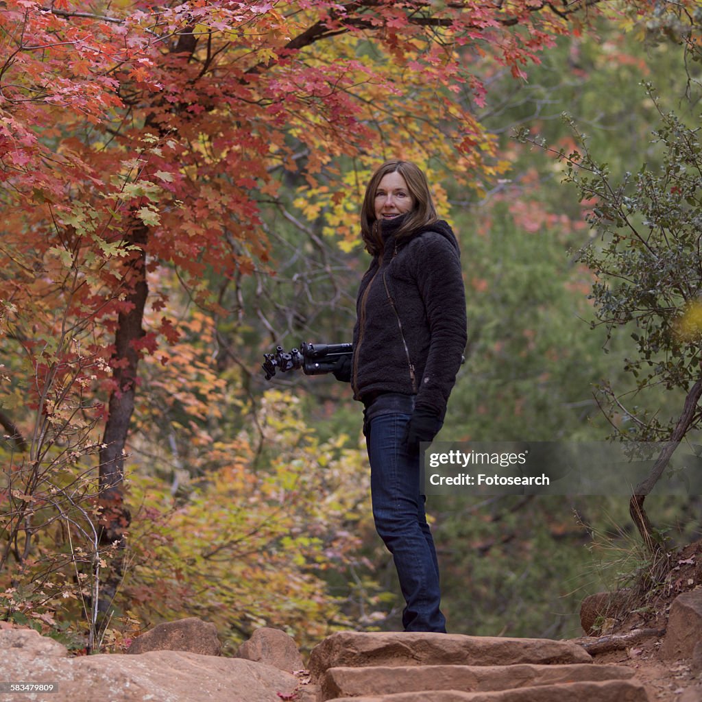 Woman standing with a tripod in a forest