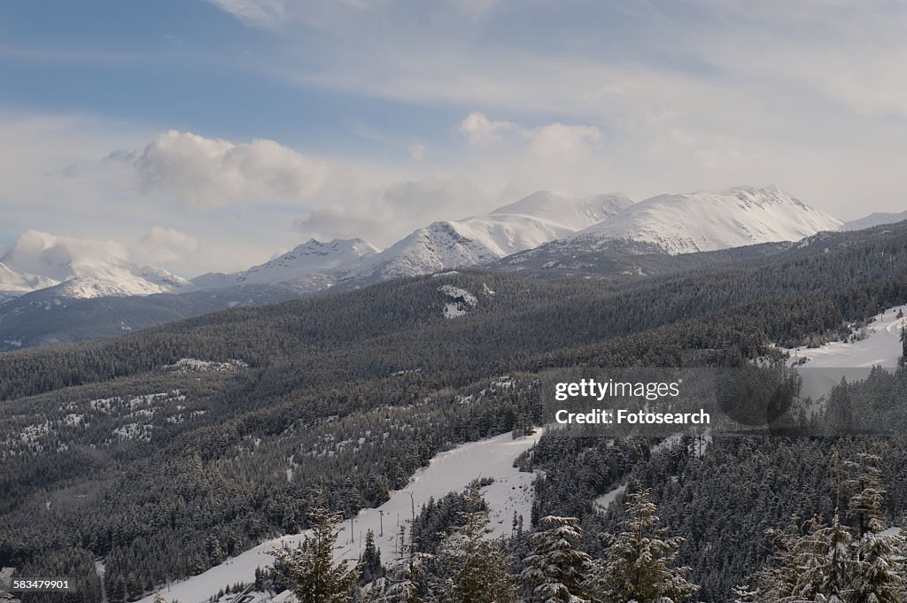 Clouds over snow covered mountains