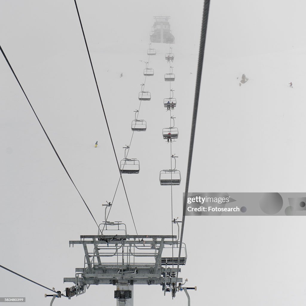 Low angle view of skiers on ski lifts