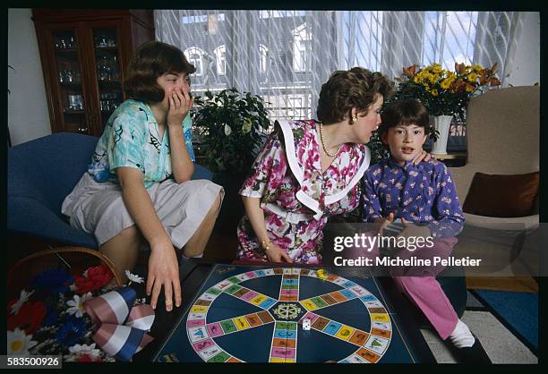 Catherine Trautmann, Mayor of Strasbourg, helps her younger daughter Magali play a game of trivial pursuit with her sister Lydie .