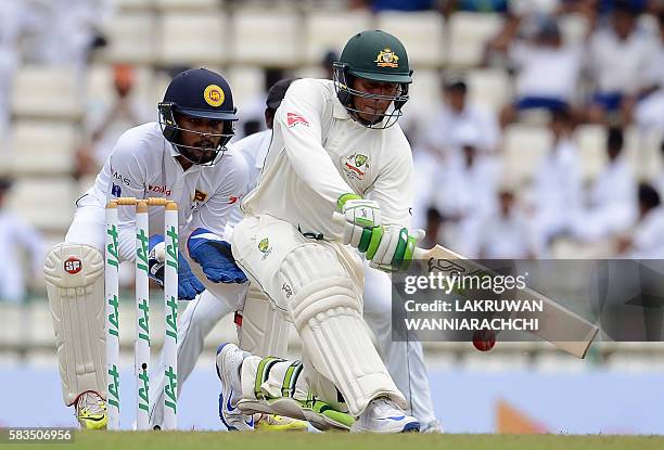 Australia's Usman Khawaja plays a shot as Sri Lanka's wicketkeeper Dinesh Chandimal looks on during the first day of the opening Test cricket match...