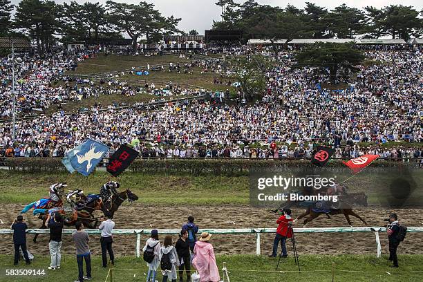 Spectators watch as samurai horsemen compete in the Kachu Keiba race during the Soma Nomaoi festival at Hibarigahara field in Minamisoma, Fukushima...