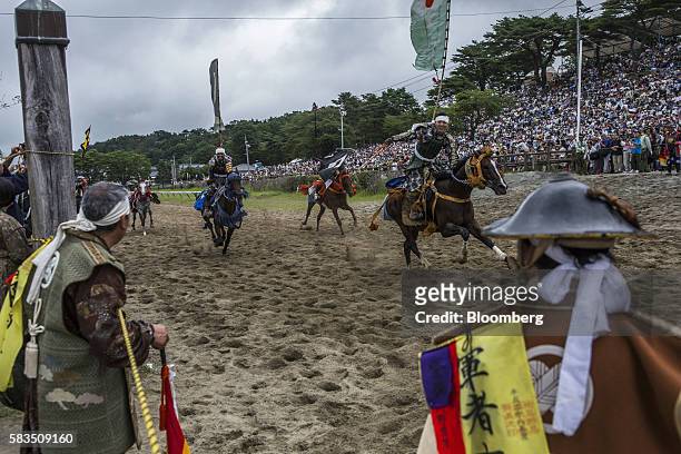 The winning samurai horseman, right, gestures in the Kachu Keiba race at the Soma Nomaoi festival at Hibarigahara field in Minamisoma, Fukushima...