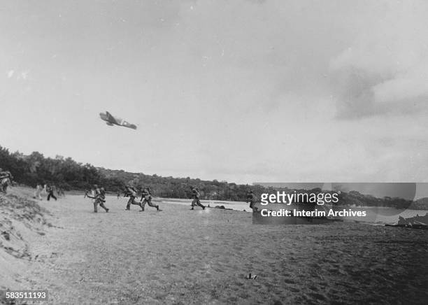 An Army P-40 gives close air support on the beach to United States troops and soldiers attacking Japanese forces at Rendova Island, of the Solomon...
