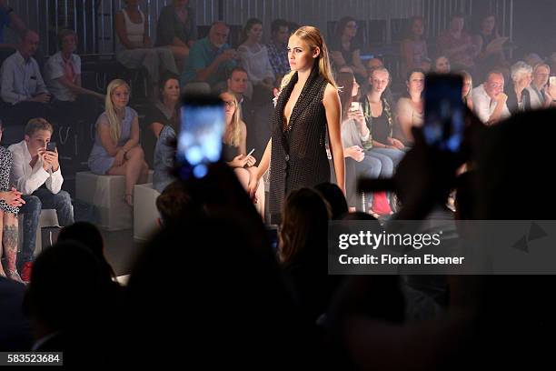 Spectators take cell phone photos as model Elena Carriere walks the runway at the 3D Fashion Presented By Lexus show during Platform Fashion July...