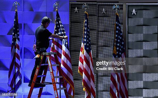 Stage hand fluffs the flags on stage before the start of day two of the Democratic National Convention in Philadelphia on Tuesday, July 26, 2016.