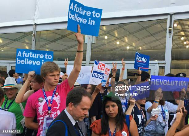 Protesters hoist signs in an improvised protest area in front of the media tents on Day 2 of the Democratic National Convention at the Wells Fargo...