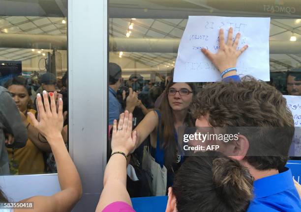 Supporters of Bernie Sanders connect hands and hold signs against the windows of one of the media tents during an improvised protest on Day 2 of the...