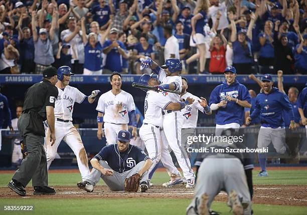 Devon Travis of the Toronto Blue Jays is congratulated by Edwin Encarnacion as Kevin Pillar leaps in the air after their game-winning run scored on a...