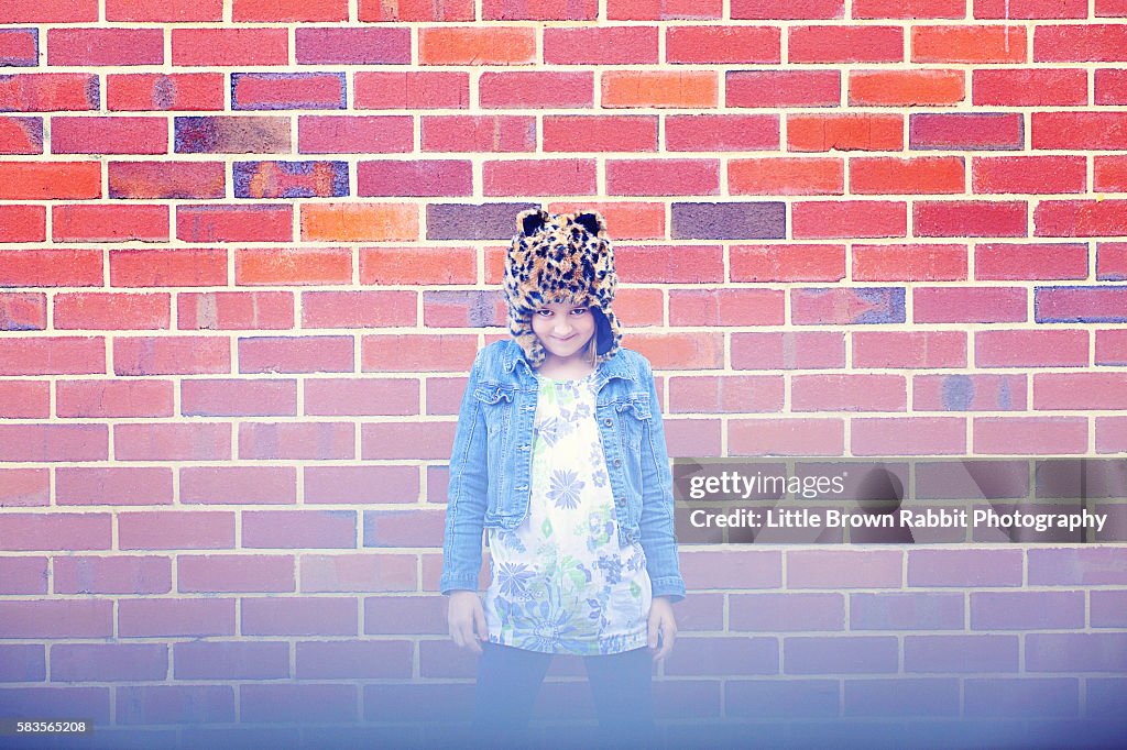 Girl Wearing a Hat Against A Brick Wall