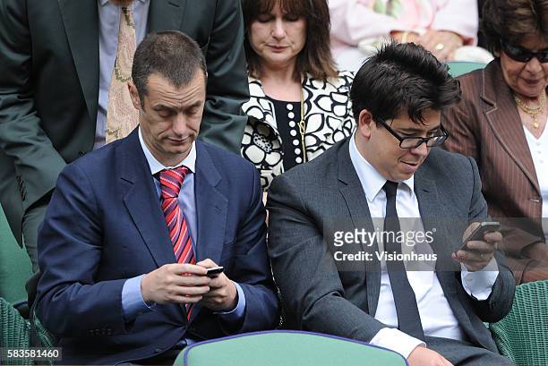 Comedians Paul Tonkinson and Michael McIntyre study their mobile phones during the Ladies Singles Final match between Serena Williams and Agnieszka...