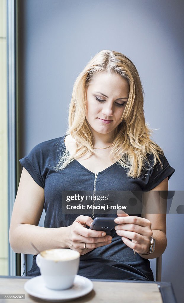 Young woman texting in a cafe